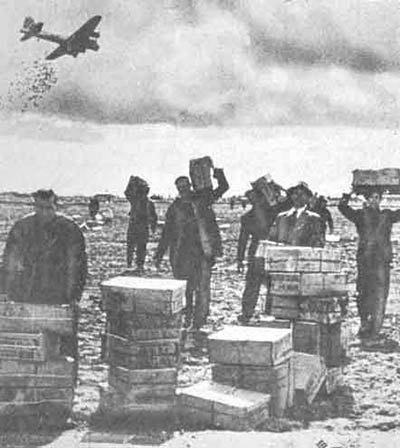 Civilians collecting scattered food boxes in a field