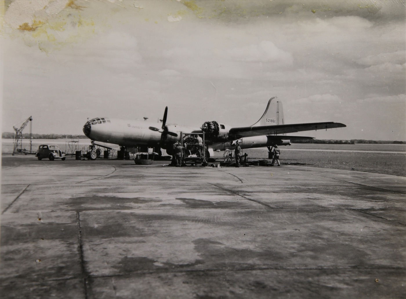 B-29 Superfortress being serviced on a hardstand with ground crews and a period car and crane