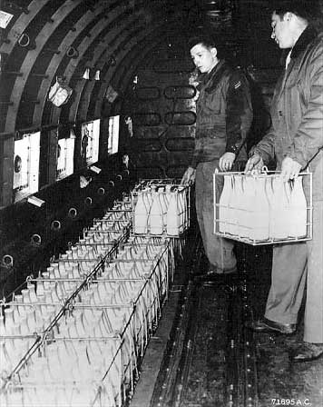 Two airmen loading crates of supplies inside the fuselage of a cargo aircraft